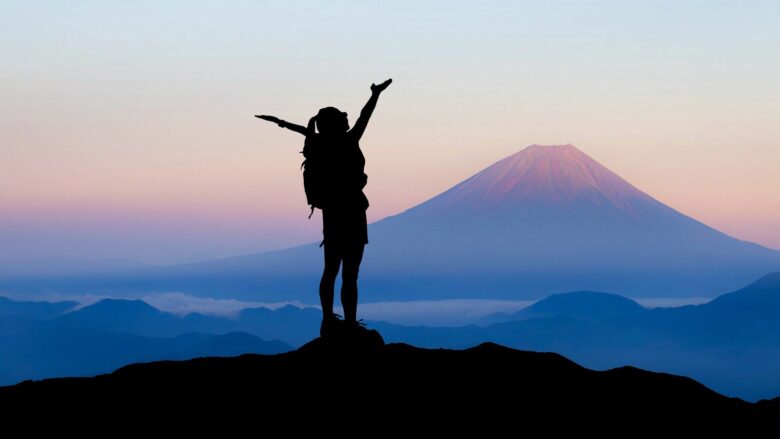 早朝の富士山を仰ぎ見る登山者